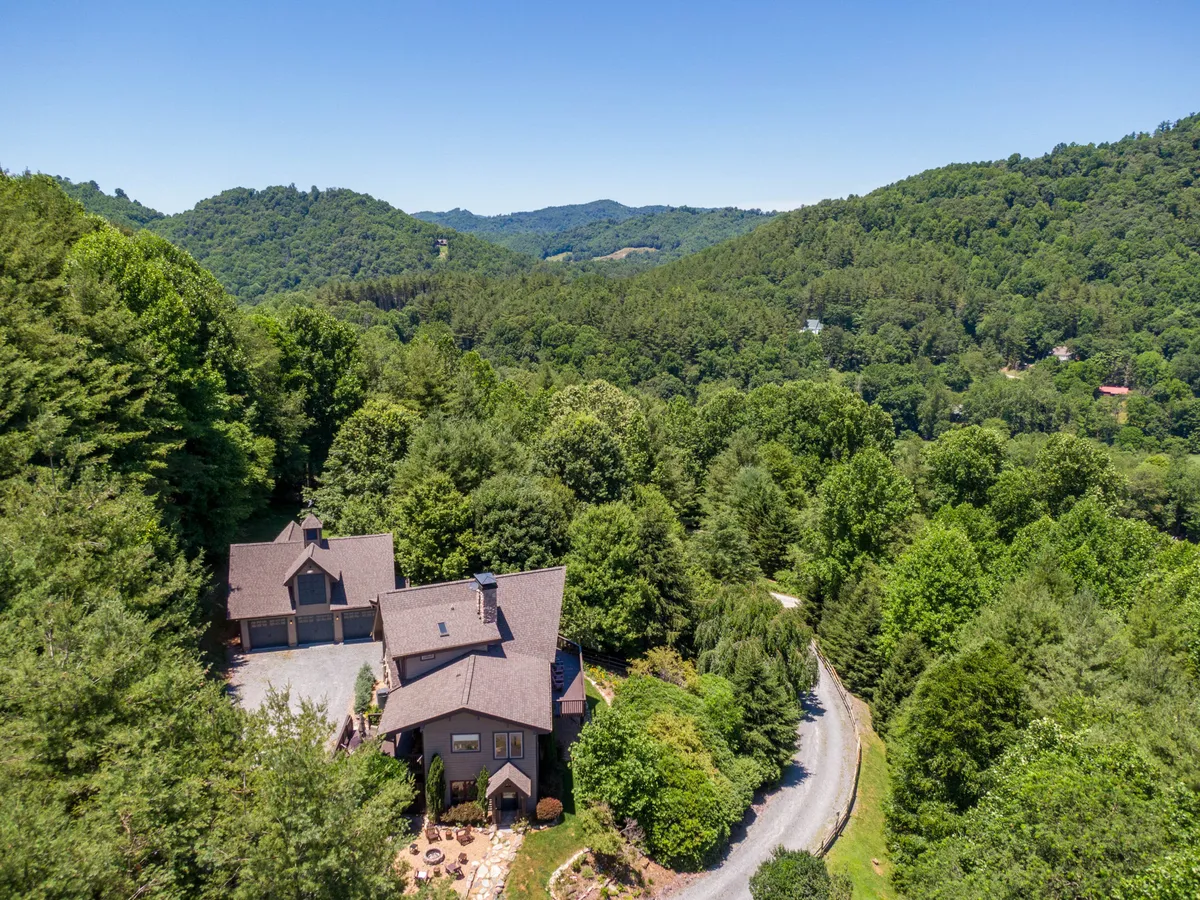 This image shows the exterior of Mountaineer Manor, set against a peaceful backdrop of surrounding trees and a spacious driveway. The house is inviting, hinting at the space available for group activities both inside and outdoors.