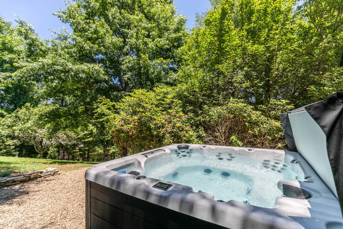 A tranquil outdoor hot tub surrounded by lush greenery. The setting feels private yet open to the night sky, perfect for evening relaxation and group bonding after a day of exploring or shared meals.