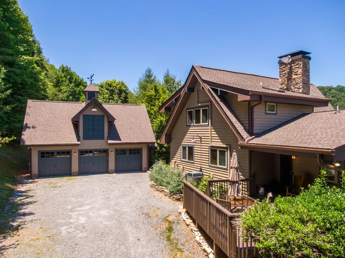 A sweeping view of the main house and garage, framed by an expansive, manicured lawn and mature landscaping. The outdoor seating area is visible, suggesting plenty of space for families, pets, and children to play. The atmosphere is inviting and park-like, encouraging outdoor activities and gatherings.